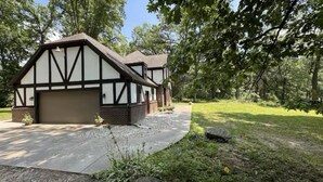 A traditional Tudor-style house with a garage, surrounded by a well-maintained lawn and trees.