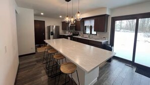 A modern kitchen with a large island, bar stools, and pendant lighting.