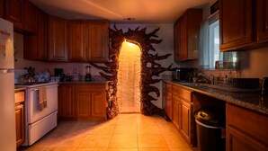 Une cuisine avec des meubles en bois, un poêle blanc et un arc en pierre original.