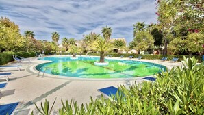 A swimming pool with lounge chairs and palm trees.
