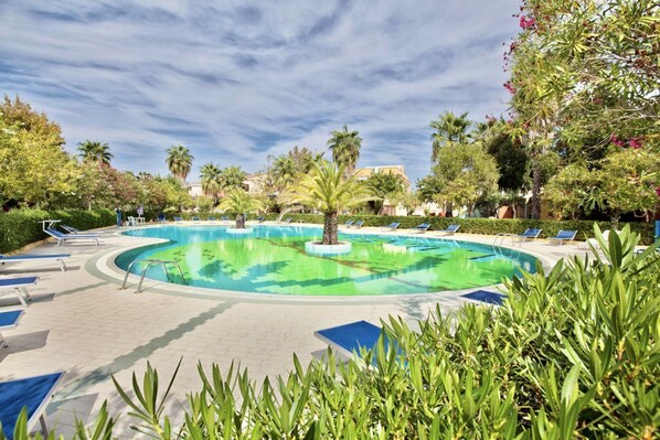 A swimming pool with lounge chairs and palm trees.