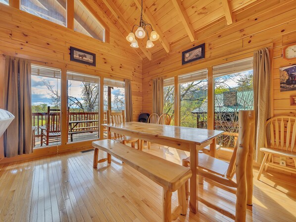 A wooden cabin with a large dining table and chairs, a bench, and a 'Welcome' sign. - Theater Room 🎬 85” TV | Hot Tub | Pool Table | Mountain Views | Near Parkway | Sleeps 12 (Pigeon Forge)