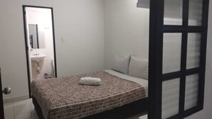 A small, clean room with a single bed, a window with blinds, a door leading to a bathroom, and a white sink. - Casa Fortel, Centro Internacional (Bogotá)