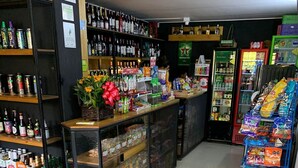 A bar area with shelves of various bottles, a counter with snacks, and a trash bin. - Casa Fortel, Centro Internacional (Bogotá)