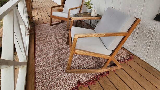 A wooden deck with two rocking chairs and a small table, surrounded by white walls and a wooden railing. - Charming studio in delightful Spring Branch for a quick, tranquil stay.   (Spring Branch)