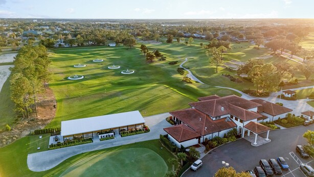 Vue aérienne d’un terrain de golf avec un club-house et un parking.