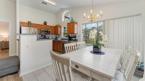 Une cuisine moderne avec des meubles en bois, un îlot central et un coin repas comprenant une table et des chaises blanches.