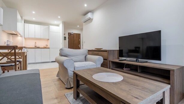 Ein modernes Wohnzimmer mit einer Couch, einem Fernseher und einem Holztisch.