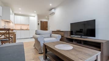 Una sala de estar moderna con un sofá, un televisor y una mesa de centro de madera.