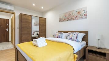 Un dormitorio con cama, mesita de noche, espejo y un cuadro en la pared.