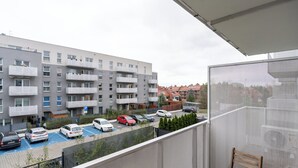 Ein Balkon mit Blick auf einen Parkplatz und ein Mehrfamilienhaus.