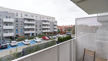 Un balcón con vista a un estacionamiento y un edificio residencial de varios pisos.