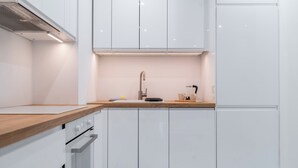 Eine moderne Küche mit weißen Schränken, einer Holzarbeitsplatte, einer Edelstahlspüle und einem eingebauten Backofen.