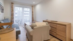A modern living room with a sofa, a wooden cabinet, and a dining table. - Park Śląski Homely Apartment #16 (Katowice)