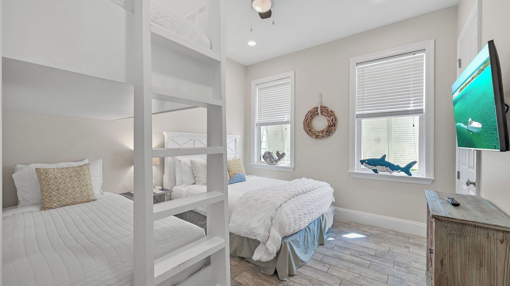 A bedroom with bunk beds, a television, and a window with a decorative wreath.