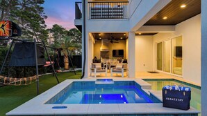 Una casa moderna con piscina, zona de estar exterior y balcón.