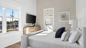 A bedroom with a large bed, a dresser, a TV, a mirror, and a window with a view of a parking lot. - 3 Blocks to Beach Sleeps 19 Pool, Spa & Golf Cart in Gulf Place (Santa Rosa Beach)