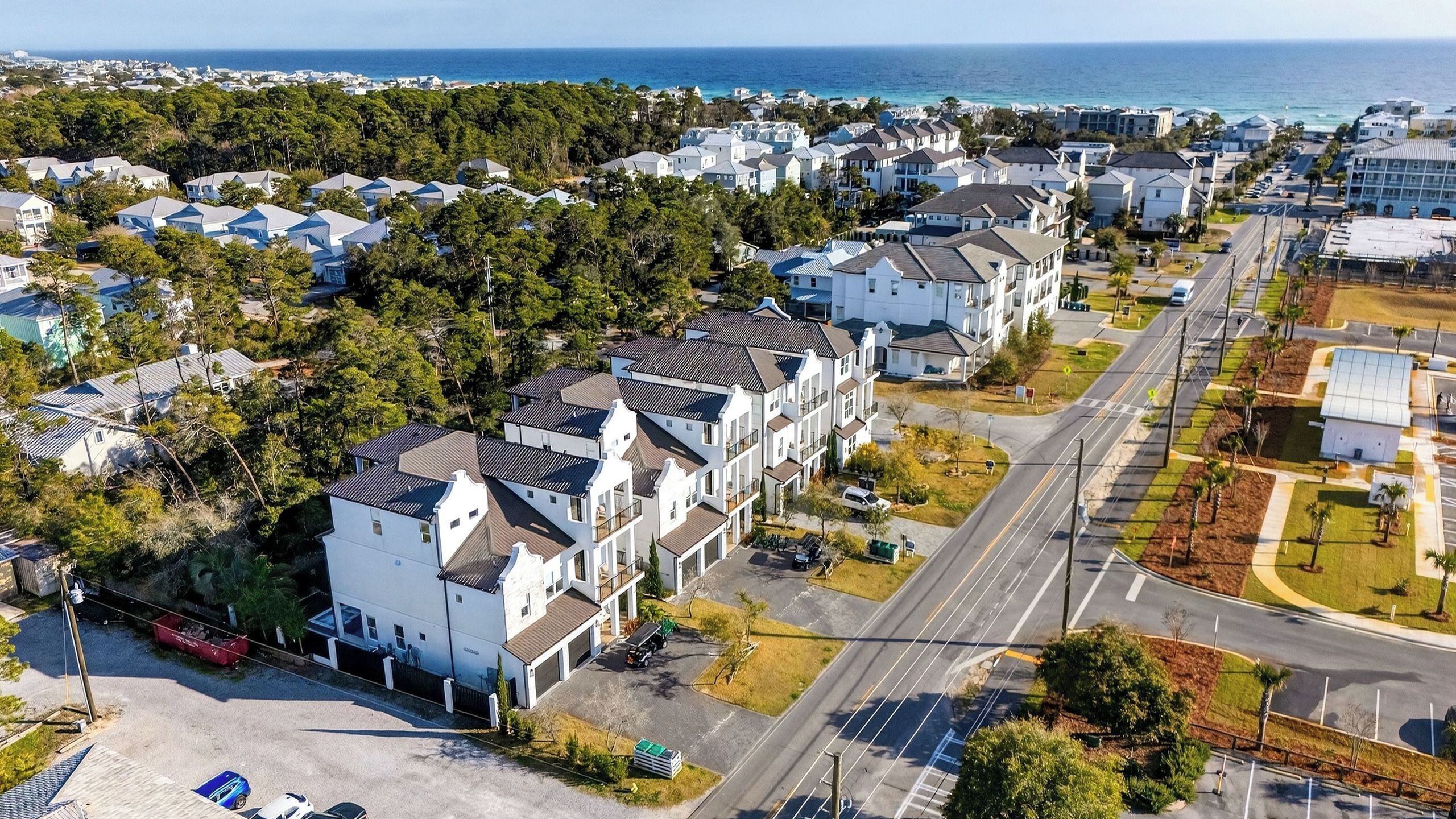 A residential area with modern houses, a road, and a view of the ocean.