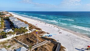 Una playa con un paseo marítimo, casas de playa y una vista despejada del océano.