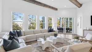 A spacious living room with a large sectional sofa, a coffee table, and a dining area with a view of the outdoors. - 3 Blocks to Beach Sleeps 19 Pool, Spa & Golf Cart in Gulf Place (Santa Rosa Beach)