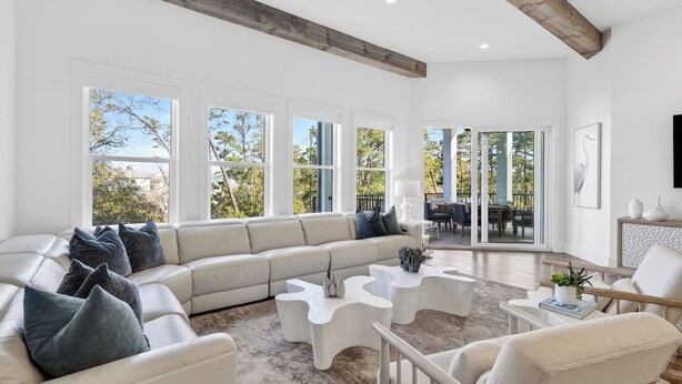 Un salón amplio con un sofá seccional grande, una mesa de centro y un comedor con vistas al exterior.