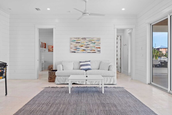 A modern living room with a white sofa, a white coffee table, and a colorful abstract painting on the wall.