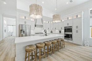 A modern kitchen with white cabinetry, stainless steel appliances, and a central island with bar stools.