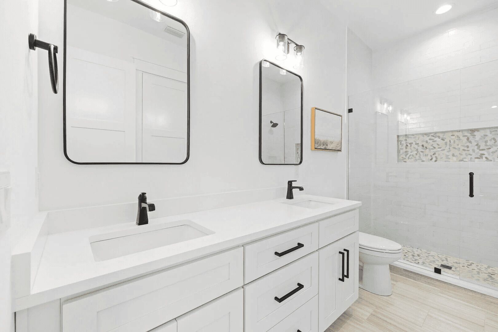 A modern bathroom with a white vanity, two mirrors, a shower, and a toilet.