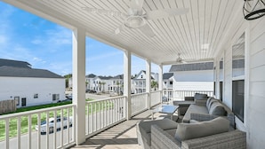 A covered outdoor area with wicker furniture and a railing.