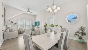 A spacious living area with a dining table, chairs, a sofa, and a ceiling fan.