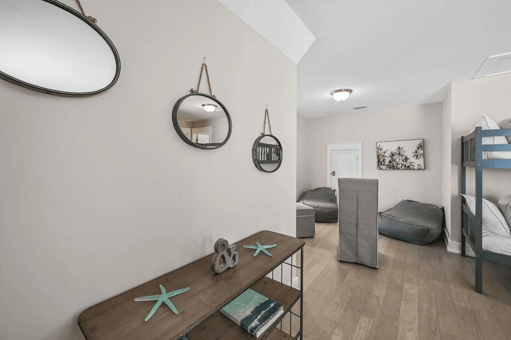 Ein kompakter Wohnraum mit Etagenbett, einem kleinen Tisch mit Seestern-Dekoration, einem Spiegel und einem an der Wand befestigten Regal.