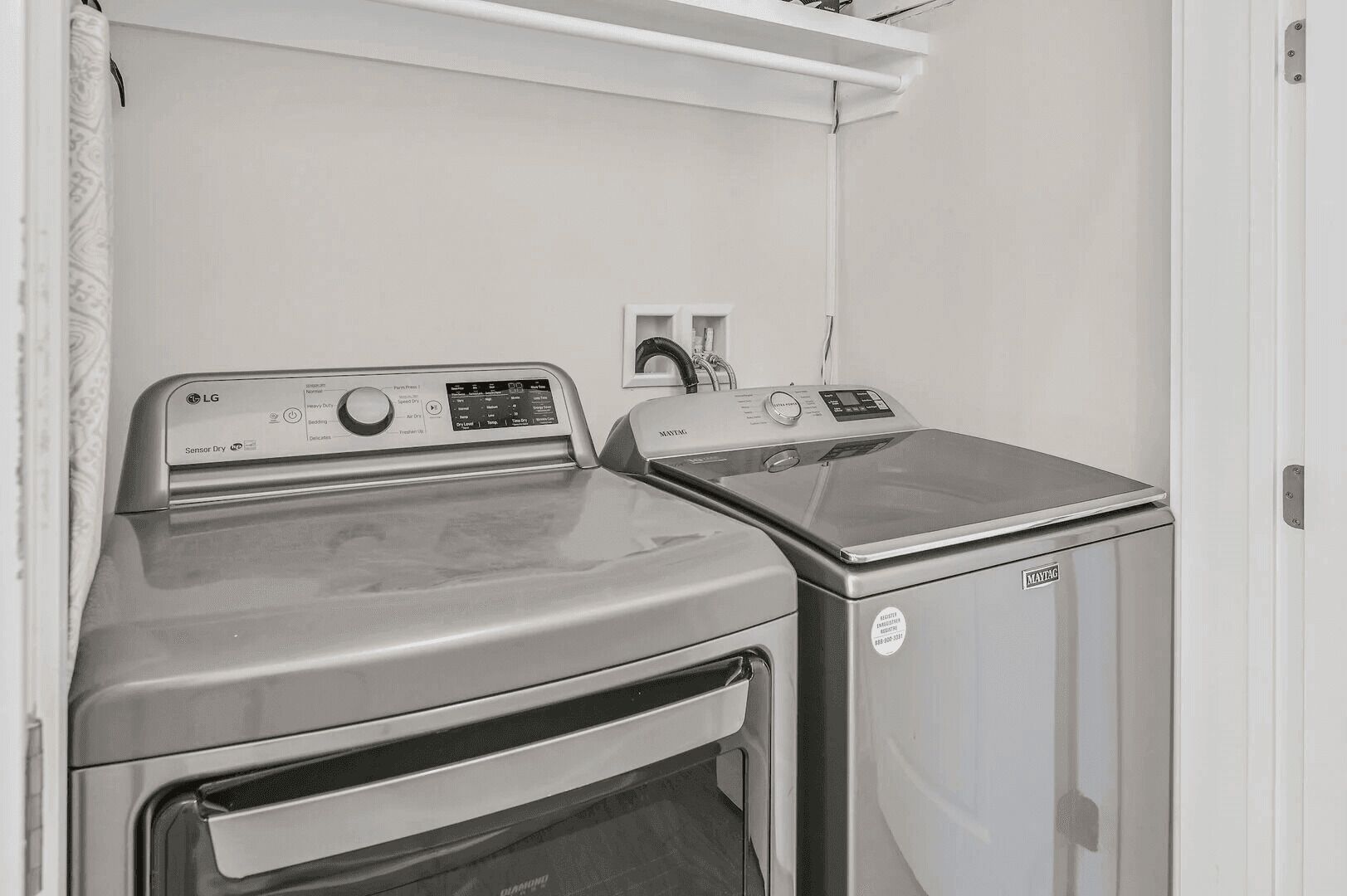 A laundry room with two washing machines, one with an LG brand and the other with a Maytag brand.