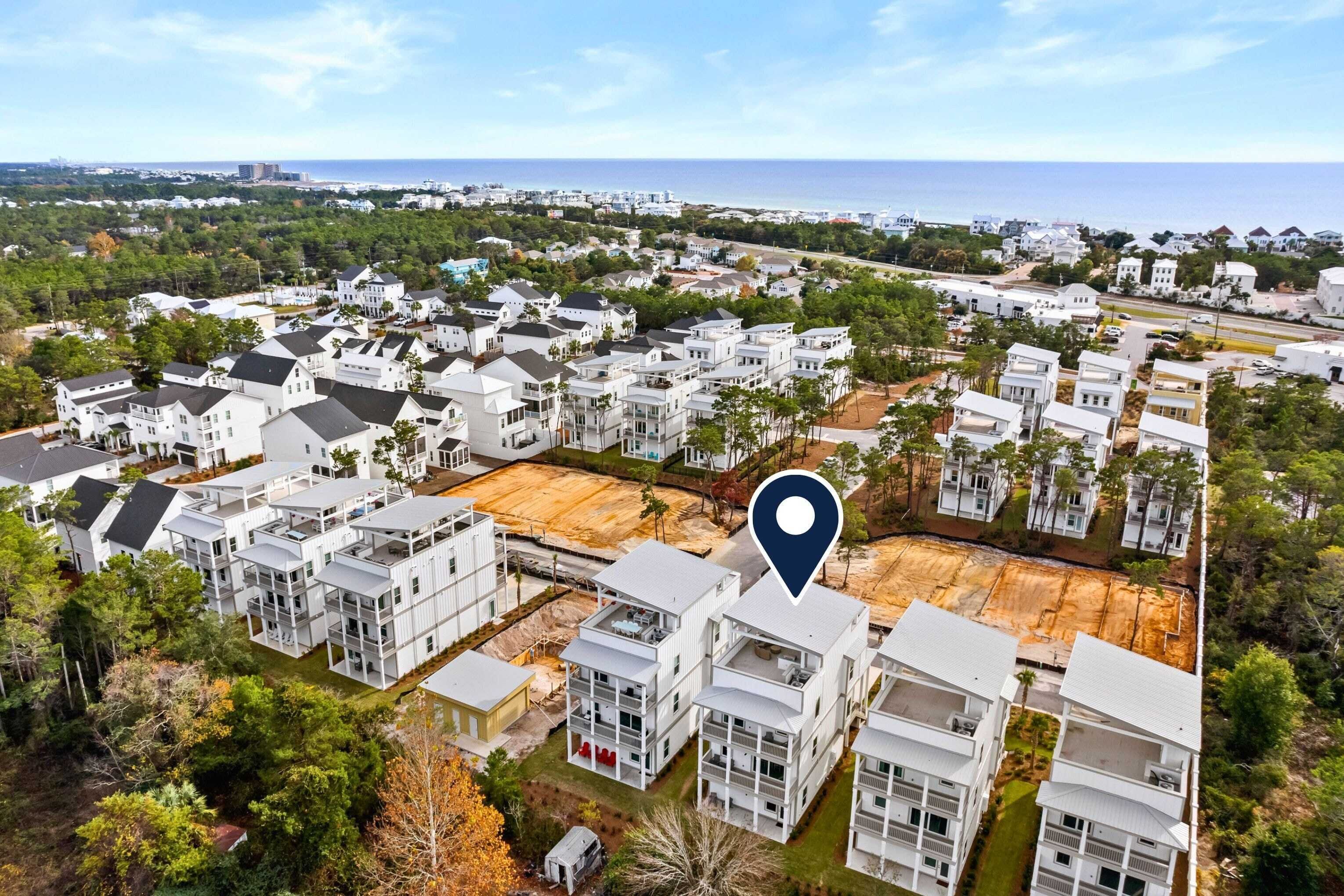 A residential area with modern white buildings, a clear view of the ocean, and a location marker.