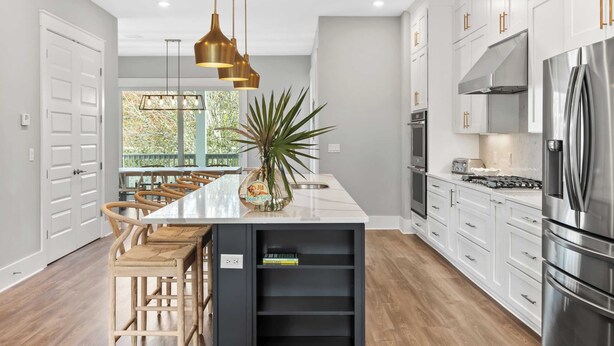 Una cocina moderna con una isla central, electrodomésticos de acero inoxidable y un amplio ventanal que proporciona luz natural.