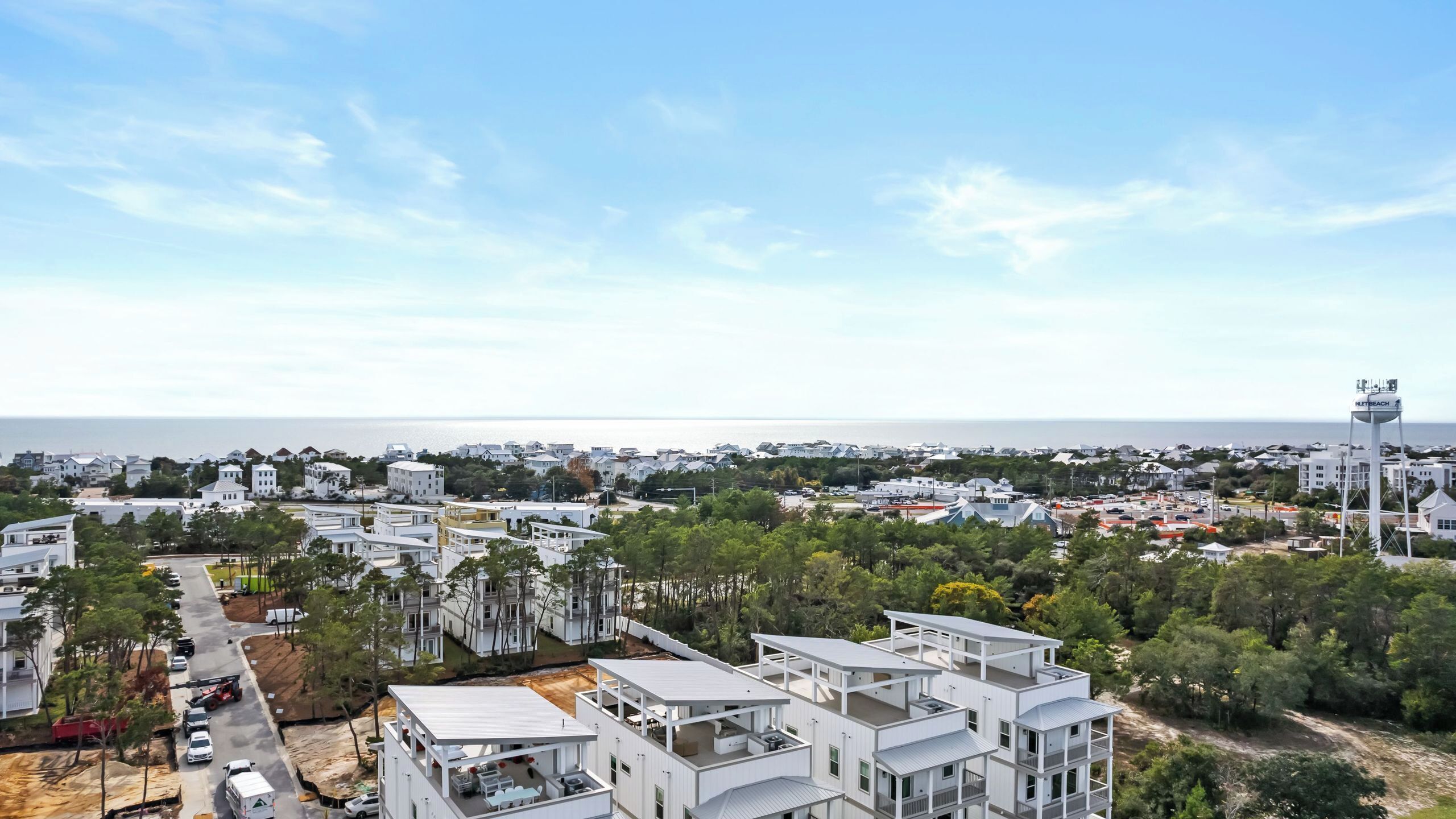 Un quartier résidentiel en bord de mer, avec des bâtiments modernes blancs, une vue dégagée sur la mer et un château d’eau portant l’inscription « NITREBEACH ».