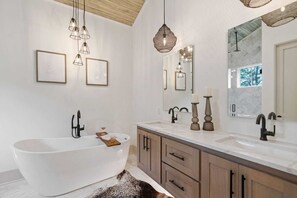 A modern bathroom with a freestanding bathtub, wooden cabinetry, and pendant lighting. - Halcyon Dayz by Avantstay New Build w/ Pool Access (Panama City Beach)