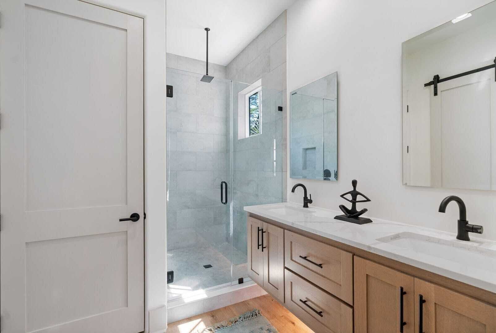 A modern bathroom with a glass shower enclosure, a double sink vanity, and a large mirror.
