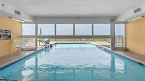 An indoor swimming pool with clear pool rules, a no diving sign, and a view of the outside.