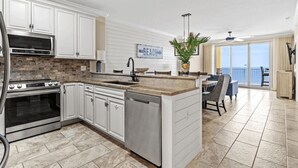 A modern kitchen with white cabinetry, a central island, and a view to a balcony.