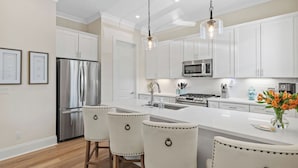 A modern kitchen with white cabinets, stainless steel appliances, and a central island with bar stools.