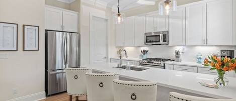 A modern kitchen with white cabinets, stainless steel appliances, and a central island with bar stools.