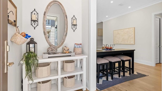 A modern kitchen with a white console table, bar stools, and a large mirror.