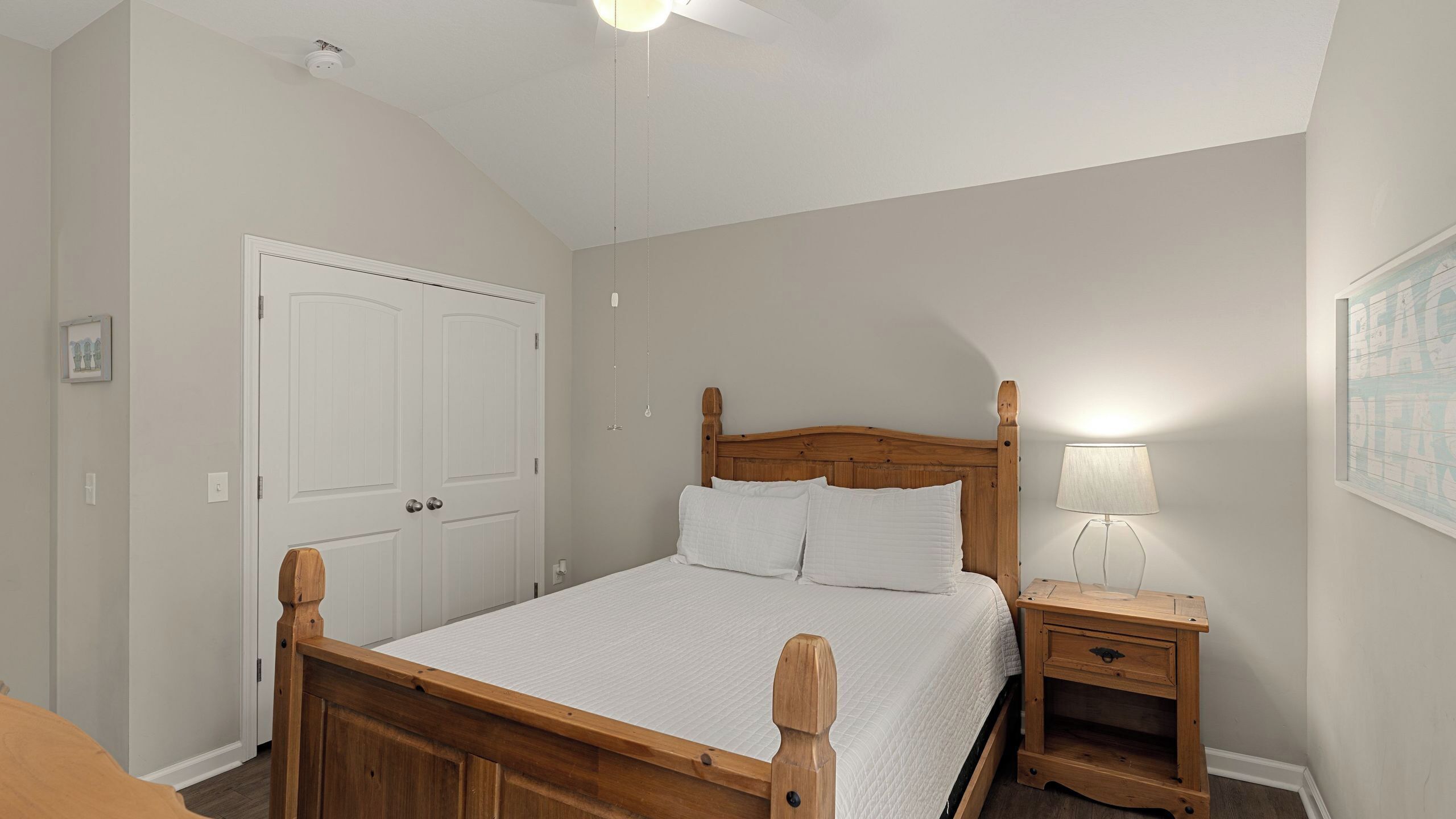 A bedroom with a wooden bed, a nightstand, a wall-mounted lamp, and a door.