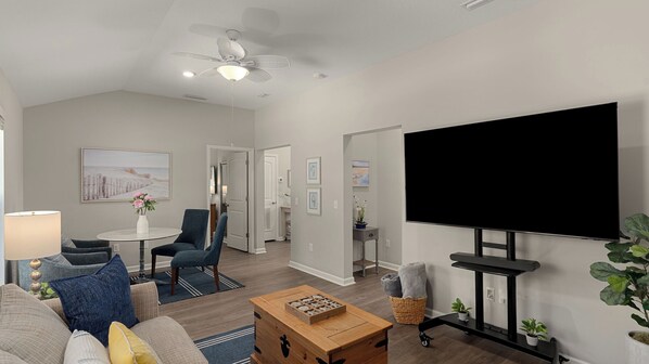 A modern living room with a flat-screen TV, a ceiling fan, and a dining area with a table and chairs. - Ocean Oasis by Avantstay Block to Beach West Pcb, Pet-friendly (Panama City Beach)