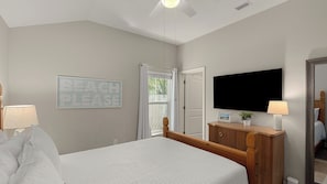A bedroom with a bed, a television, a dresser, and a sign on the wall.