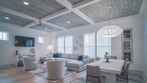 Ein geräumiges Wohnzimmer mit einer großen Eckcouch, einem Esstisch und einem Deckenventilator.