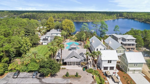 A residential area with houses, a swimming pool, and a lake in the background.