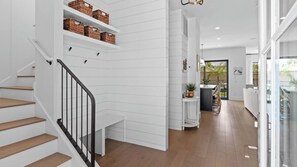 Ein modernes Interieur mit Treppe, weißen Wänden und Blick ins Freie.