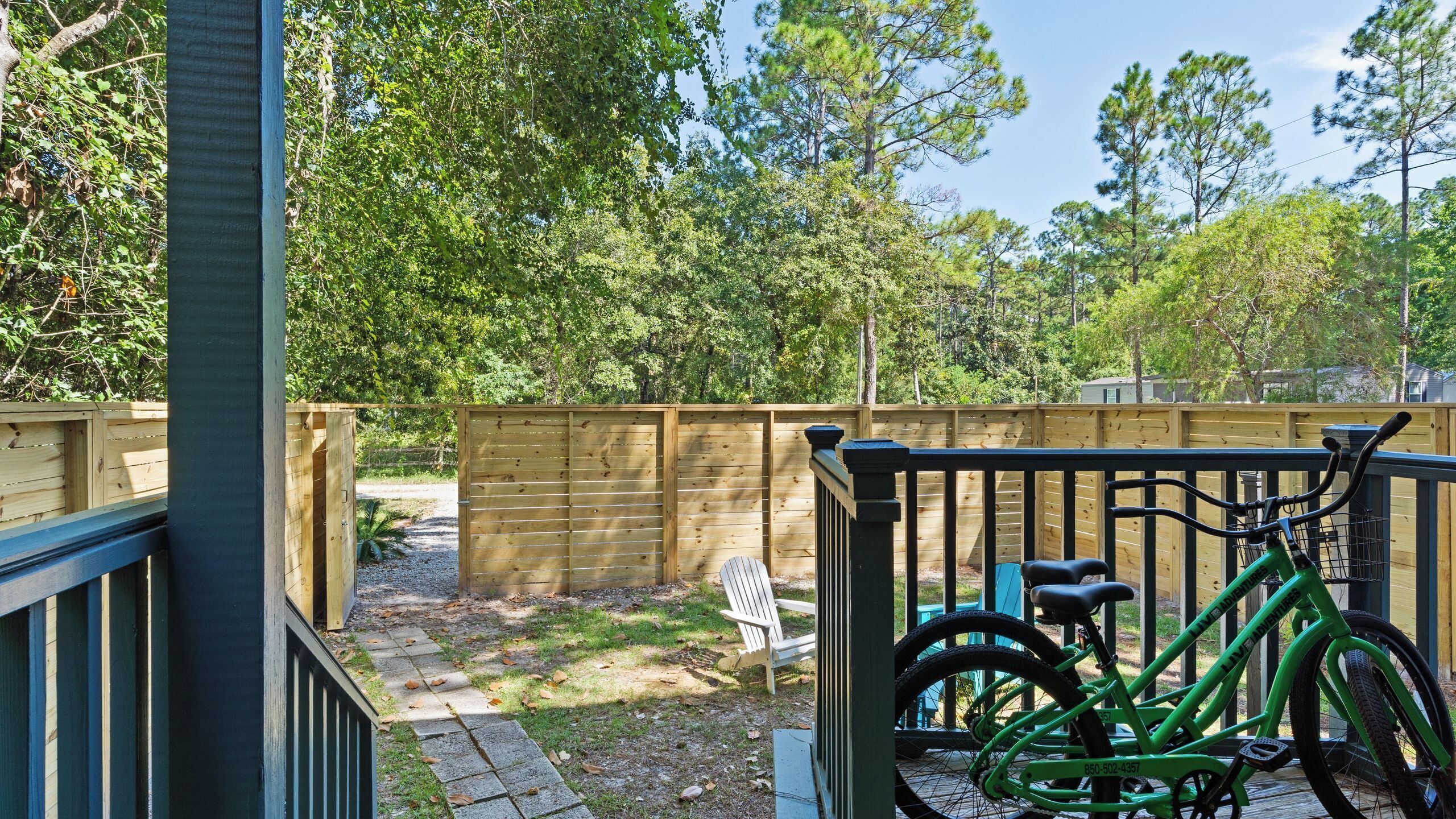 A wooden deck with a bicycle, a bench, and a wooden fence.