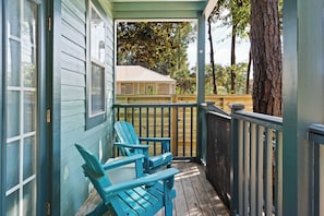 A porch with two blue Adirondack chairs, a wooden deck, and a view of a house with a white roof. - Coastal Soul 393 by Avantstay Near Boat Ramp & Bay, Private Yard (Santa Rosa Beach)